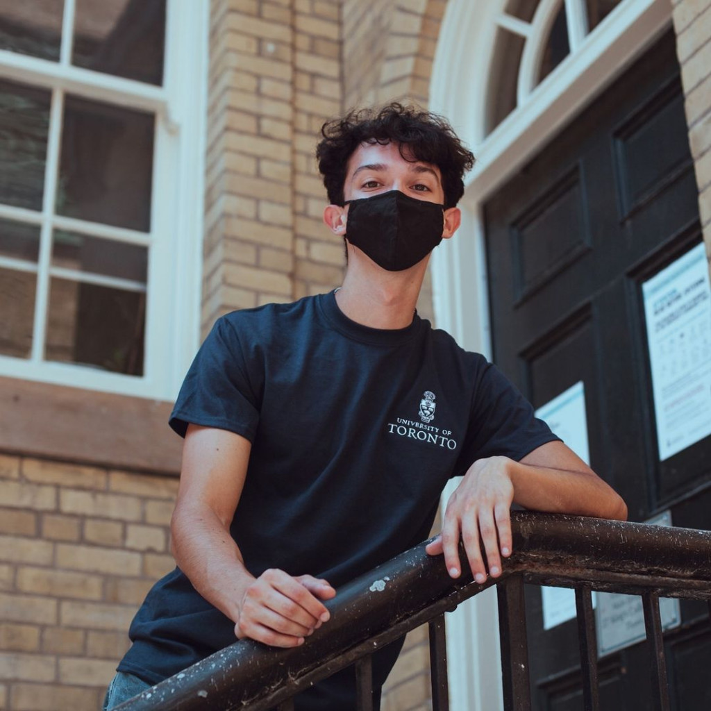 Student standing near a building wearing a dark blue University of Toronto tshirt