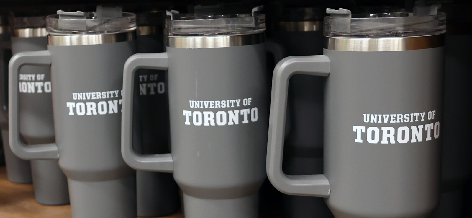 Row of grey University of Toronto commuter mugs in white University of Toronto word marks