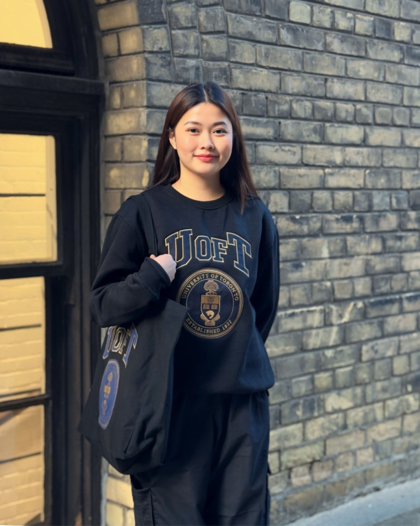 model wearing navy U of T crewneck carrying U of T Navy Tote